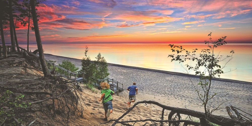 colourful-sunset-lake-beach-michigan-man-and-toddler-running-on-sand-summer-2022